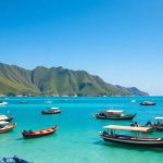 Boats in Labuan Bajo harbor with green hills.